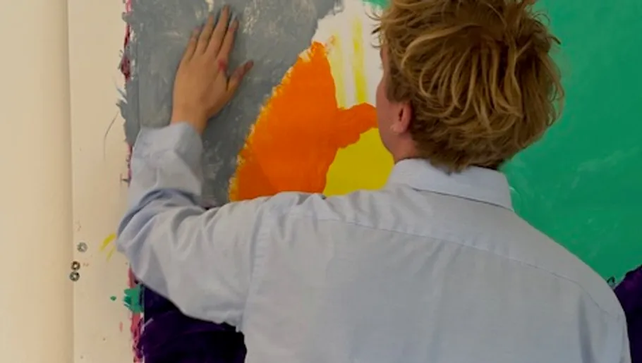 Person painting colorful abstract artwork on wall.