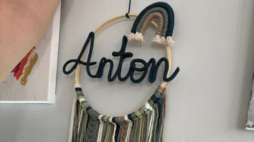 Gewebtes Namensschild 'Anton' mit Regenbogendekoration.