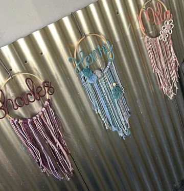 Embroidered yarn decorations hanging on metal wall.