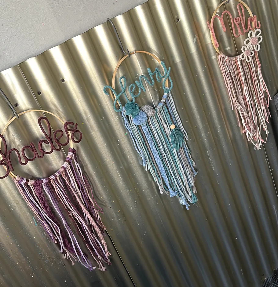 Gestickte Garn-Dekorationen an Metallwand aufgehängt.