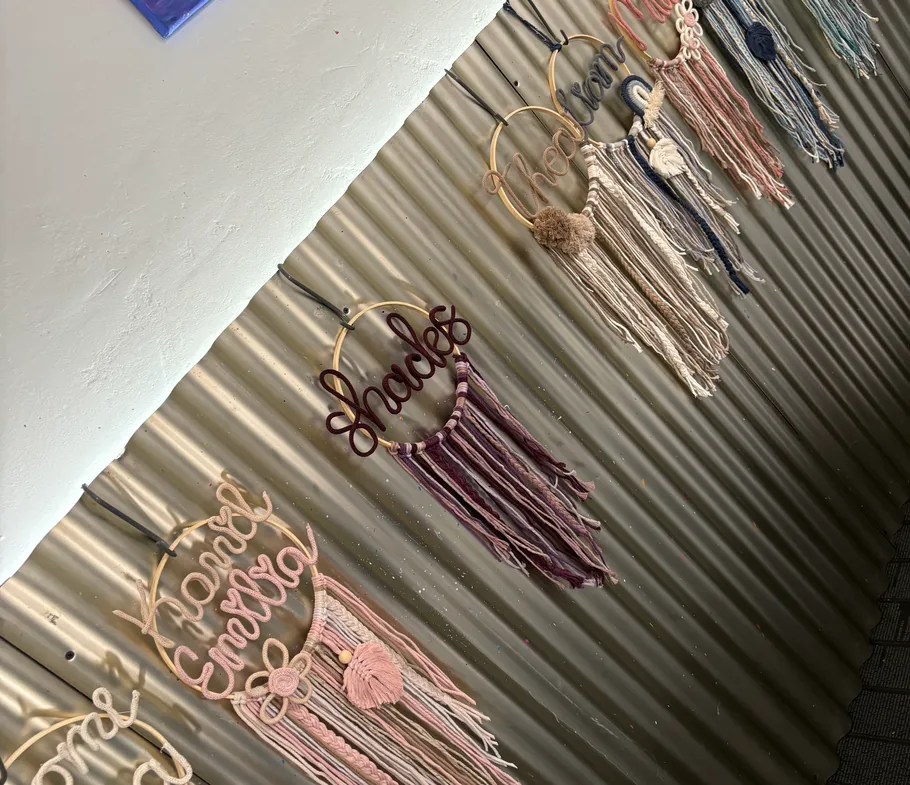 Decorative yarn hangings on corrugated metal wall.