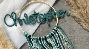 Namensschild aus geflochtenem Garn auf rundem Rahmen.