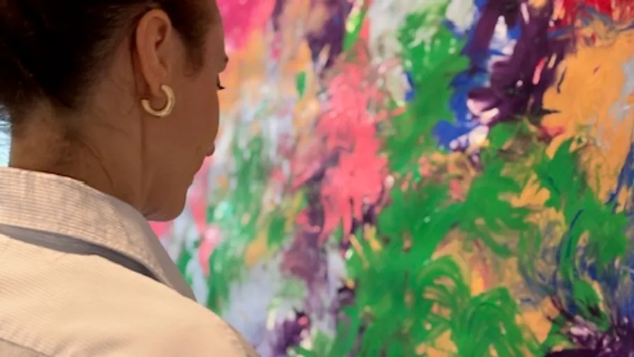 Person observing colorful abstract painting closely.