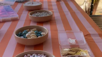 Perlen und Schmuckstücke auf gestreiftem Tischtuch.