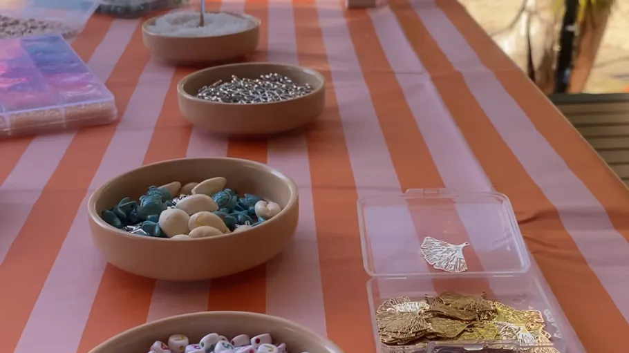 Perlen und Schmuckstücke auf gestreiftem Tischtuch.