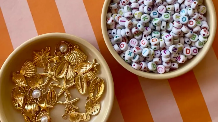 Schalen mit goldenen Anhängern und Buchstabenperlen.