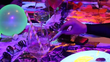 Table set with drinks and glowing party decorations.