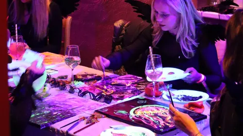 Women painting at a dimly lit event.