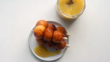 Mini donuts on sticks with sauce jar.