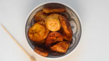 Fried plantain slices in a decorative bowl.