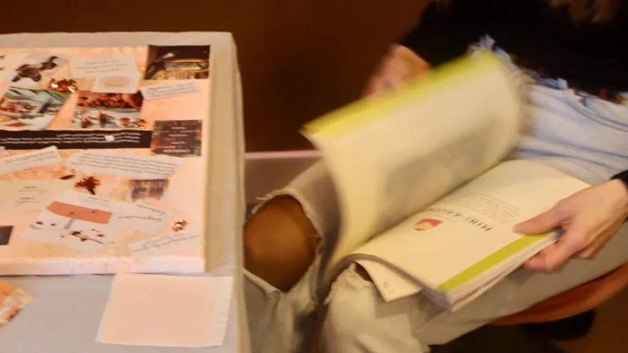 Person blättert Buchseiten am Tisch um.