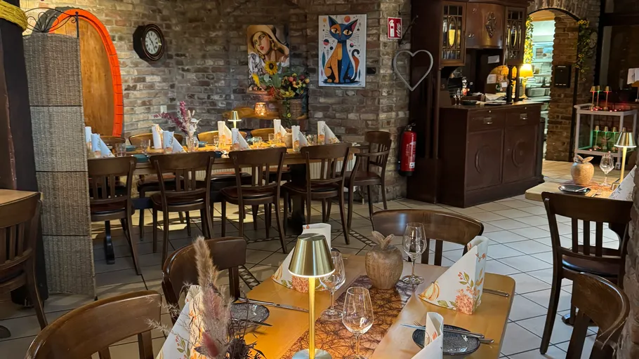 Gemütliches Restaurant mit gedeckten Tischen und Gemälden.