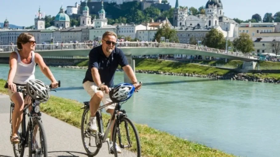 Two people cycling along a riverside path.