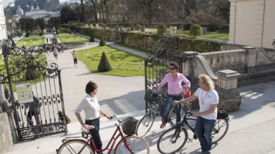 Three people biking in a garden entrance.