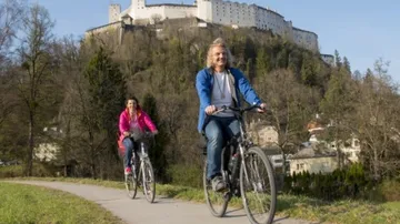 Zwei Personen fahren Fahrrad nahe einer Burg.