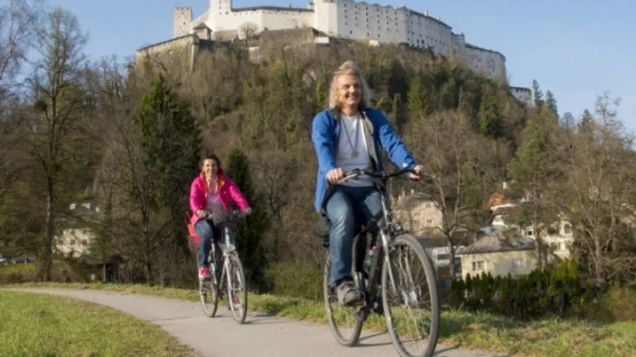 Two people cycling on a path near castle.