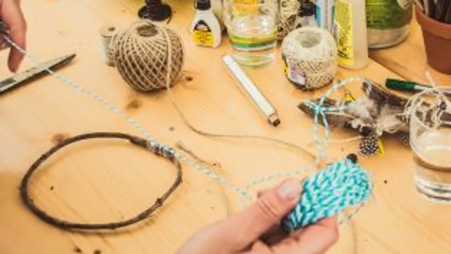 Hands crafting with string on wooden table.