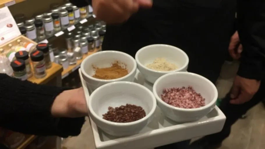 Person holds four bowls with spices in store.
