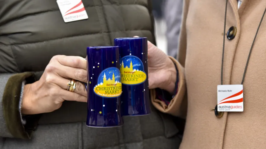 Two people holding Salzburg Christmas market mugs.