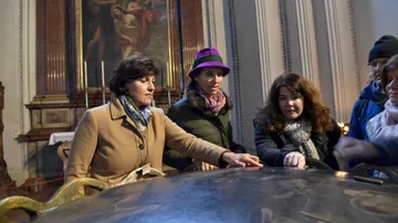 People gathered around a tomb in a church.