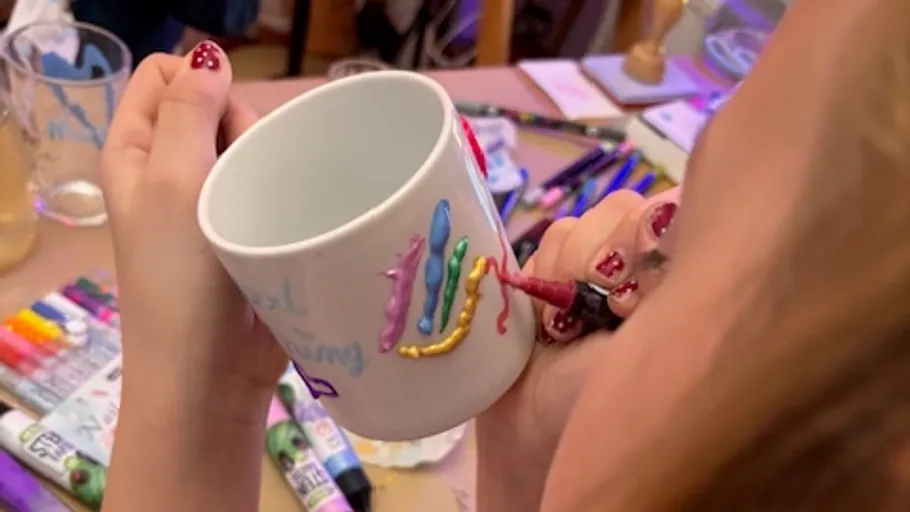 Hand verziert weiße Tasse mit Farbstiften.