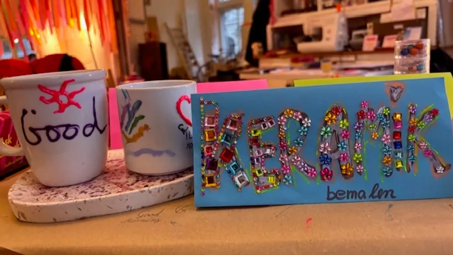 Dekorierte Tassen und buntes Keramikschild drinnen.