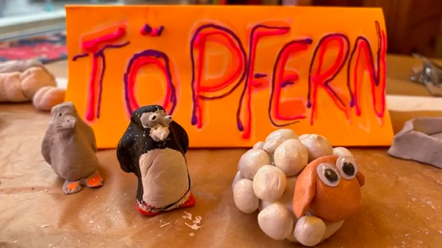 Clay animals with 'Töpfern' sign in background.