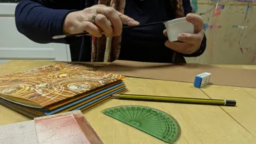 Person malt mit Pinsel, Bücher und Werkzeuge.