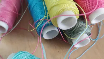 Colorful spools of thread on wooden table.