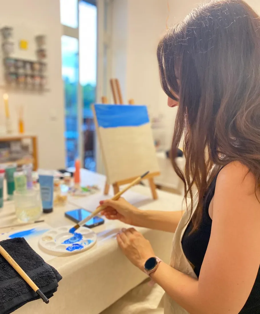 Woman painting on canvas in bright studio.