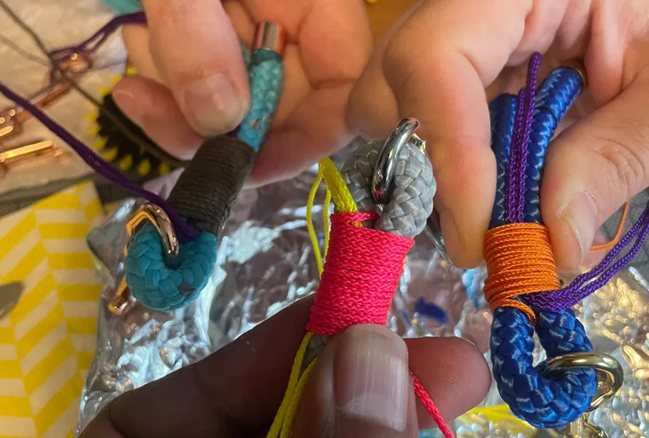 Hands crafting colorful rope accessories.