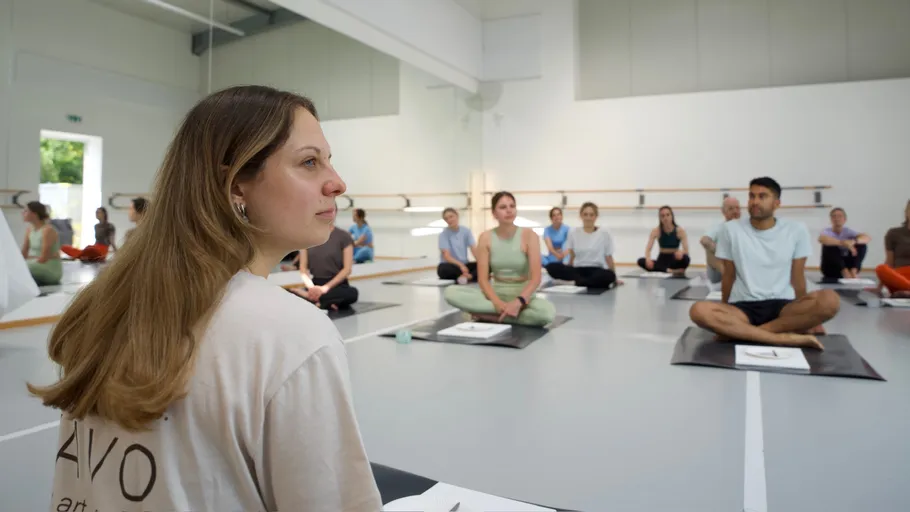 People sitting on yoga mats in a studio.