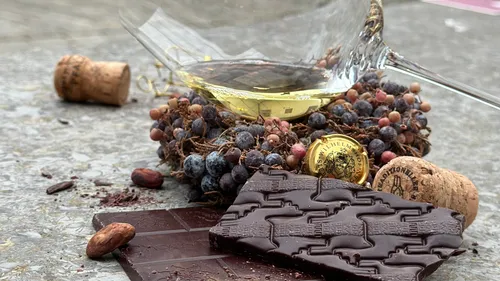 Wine glass with chocolate and corks on stone.