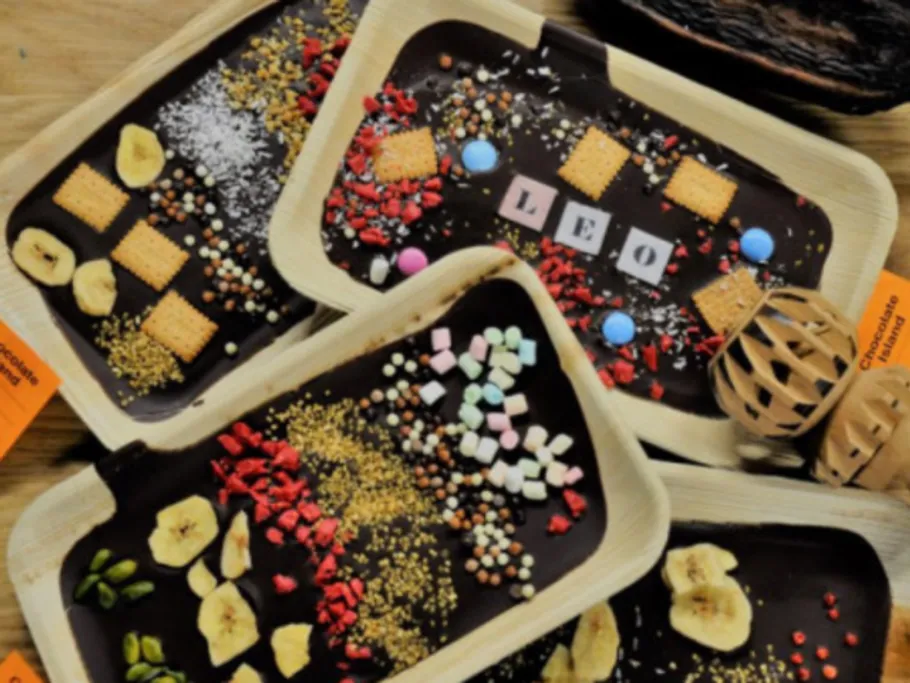 Auf diesem Bild sind drei Schokoladentafeln zu sehen, welche unterschiedlich verziert wurden: Mit nüssen, Buchstaben (Leo), Keksen, Samen, Streusel, Marshmallows