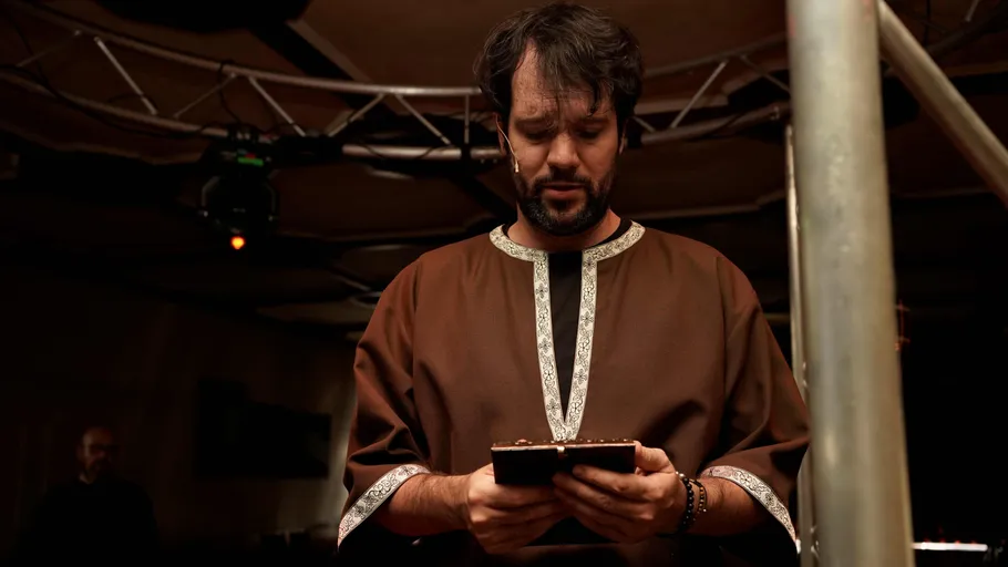 Mann liest Skript in schwach beleuchtetem Raum.