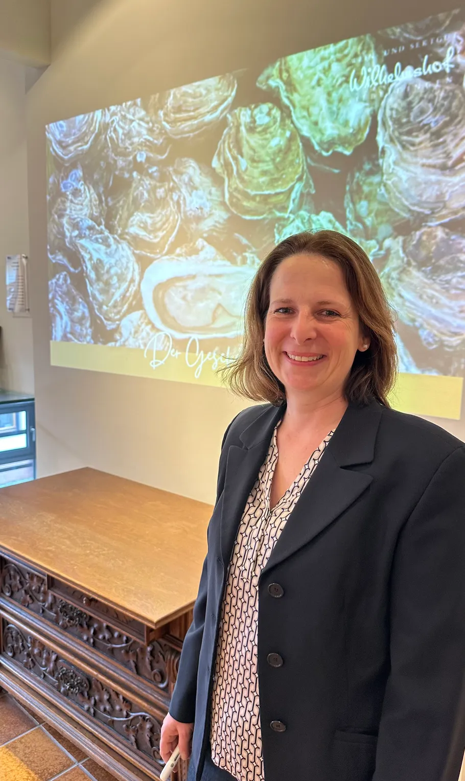 Smiling woman standing near presentation screen.
