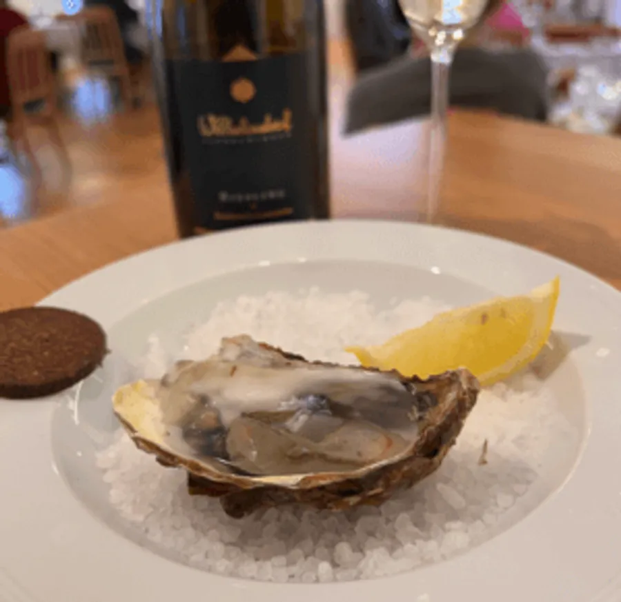 Oyster on salt with lemon and bottle nearby.