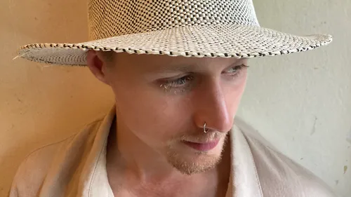 Person wearing hat, looking down, indoors.