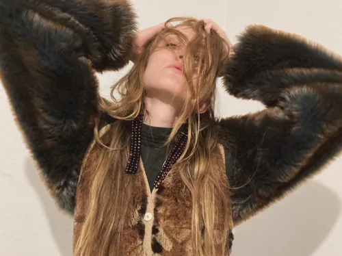 Person wearing fur coat poses indoors.