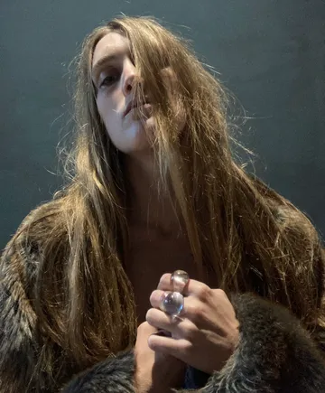 Person mit langen Haaren im Pelzmantel.