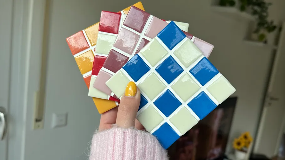 Hand holding colorful tile samples indoors.