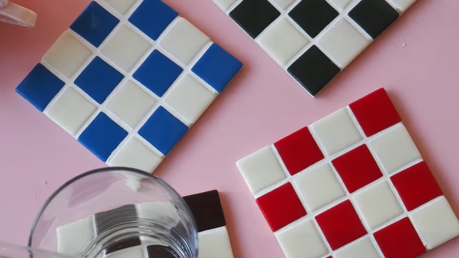 Colorful tile coasters on pink table.