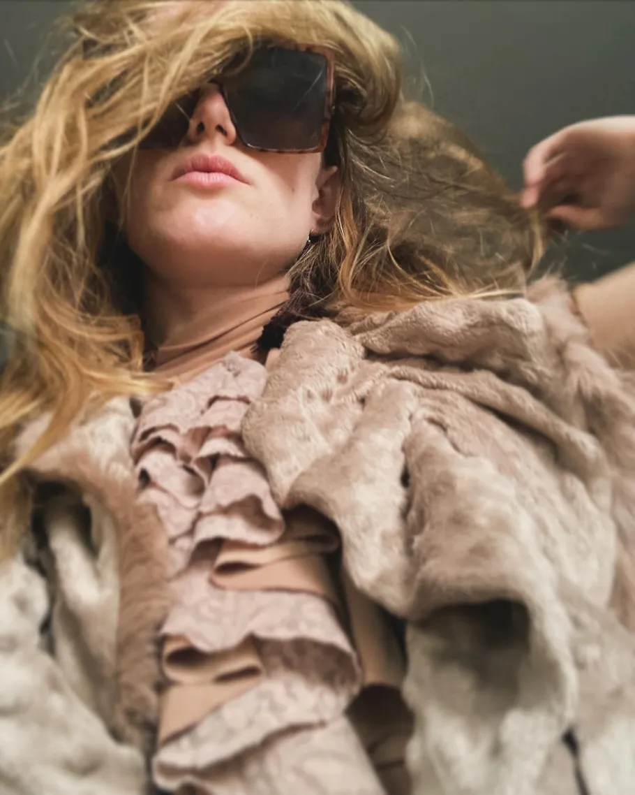 Frau trägt Sonnenbrille in stilvoller Kleidung.