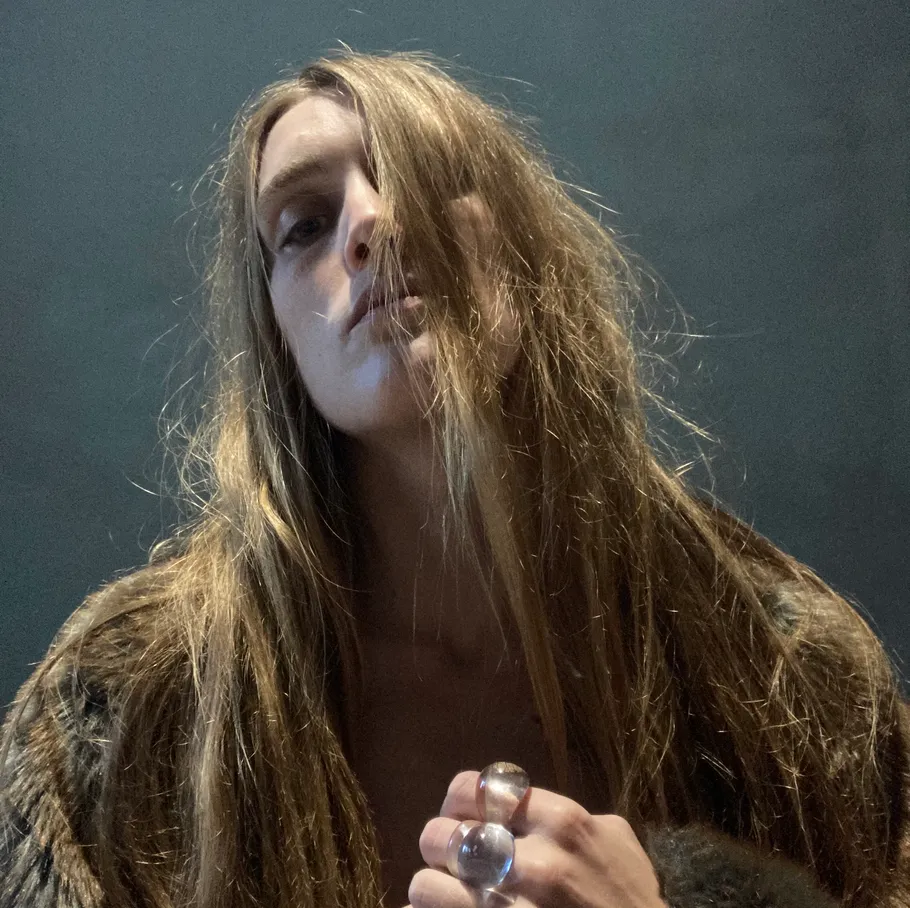 Person wearing fur coat, holding hands, indoors.