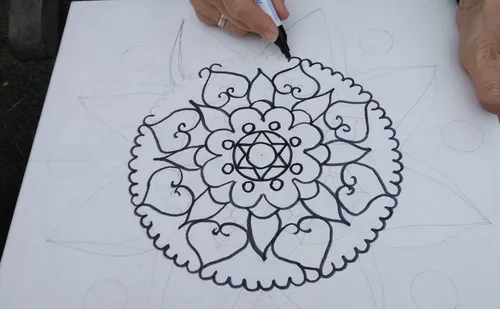 Hand zeichnet filigranes Mandala auf Leinwand.