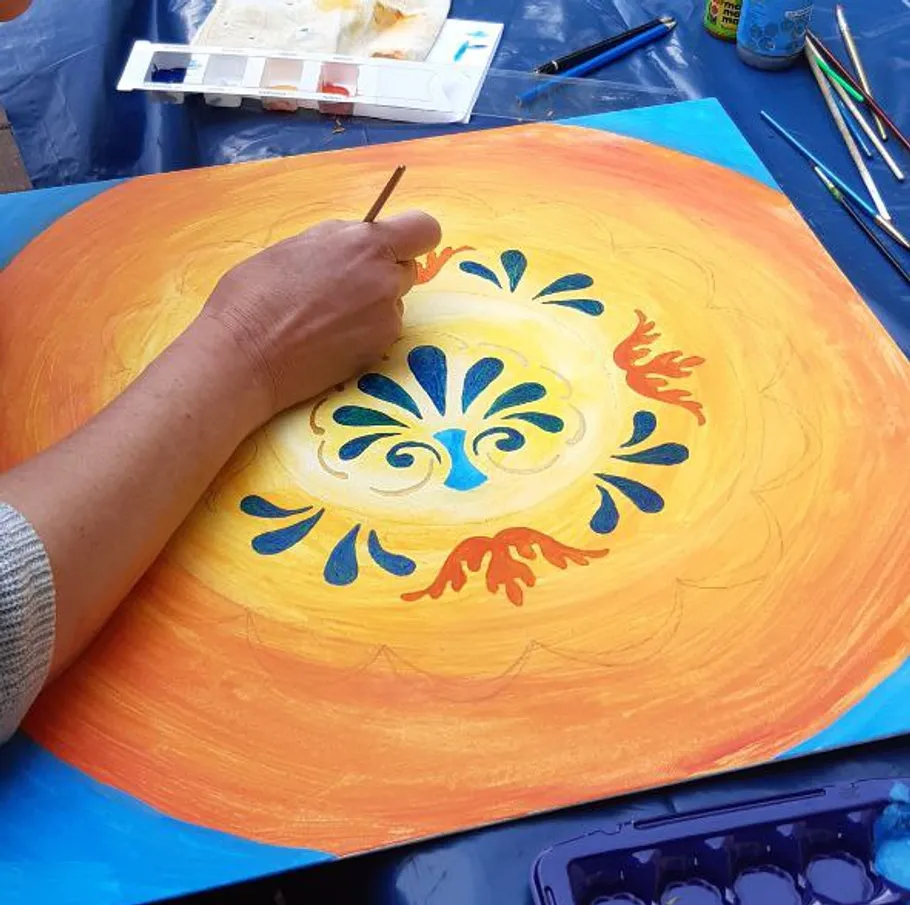 Person painting vibrant, colorful mandala design.