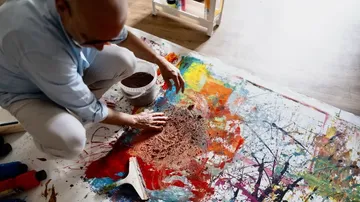 Person erstellt abstrakte Kunst mit bunten Farben.