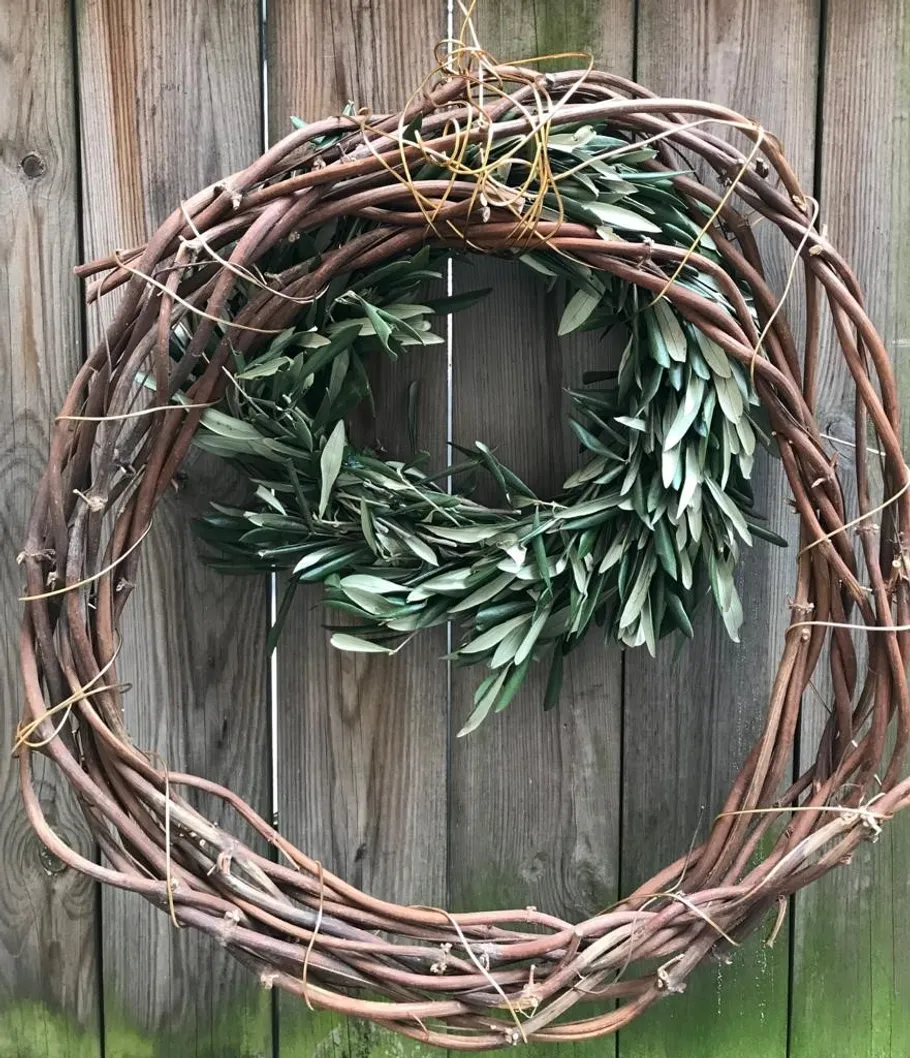 Wooden wreath with leaves on wooden fence.