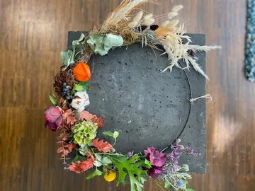 Floral wreath on concrete block, wood floor.