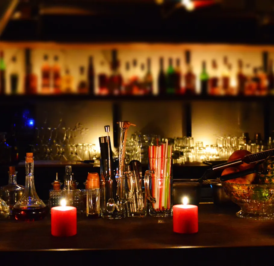 Candles and bar tools on a dimly lit counter.